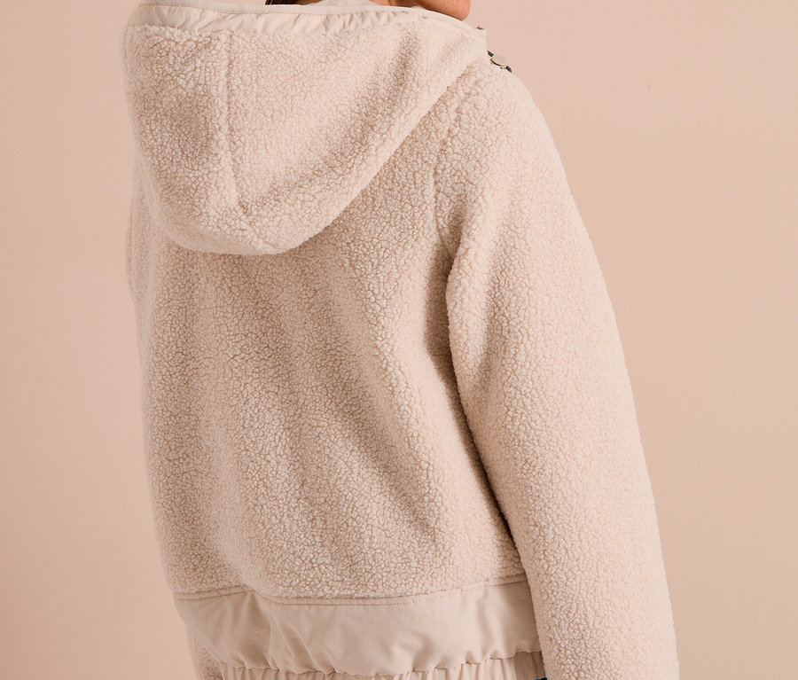 Frau von hinten, leicht zur Seite gedreht, trägt eine hellbeige CECIL Jacke aus Teddyfleece mit Kapuze und Jeans.