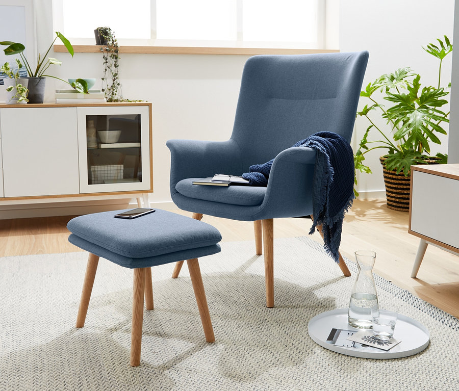 Blauer Sessel mit Fußhocker steht im Wohnzimmer.