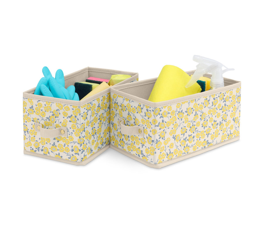 Zwei kleine Schubladen-Ordnungsboxen mit Blumenmuster, eine mit blauen Handschuhen und Schwämmen, die andere mit gelbem Lappen, Schwämmen und Spray.