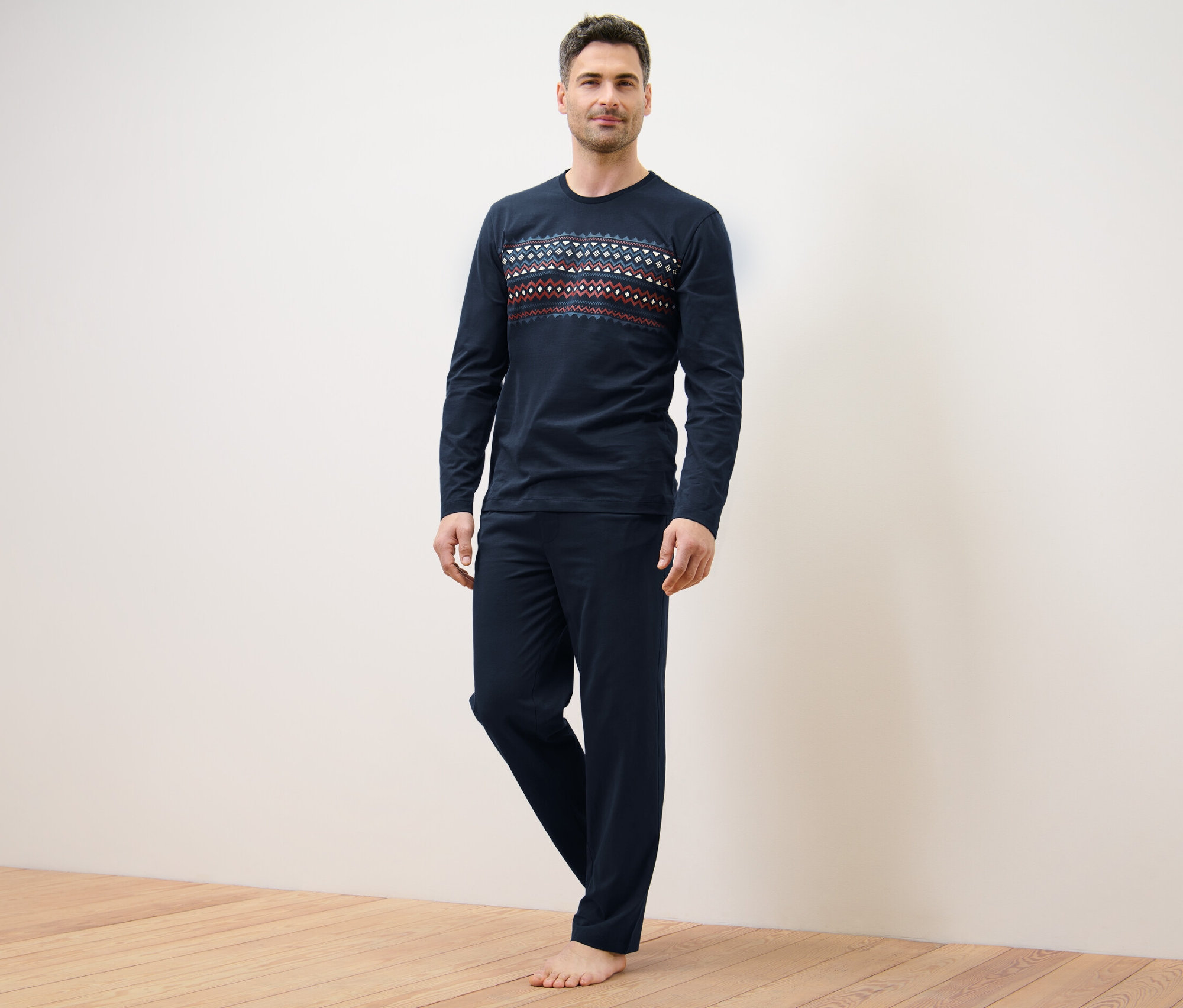 Mann steht und trägt einen dunkelblauen Pyjama.