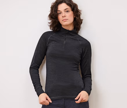 Frau posiert in anthrazitfarbenem Funktionsshirt mit RWS-zertifizierter Wolle und dunkler Hose.