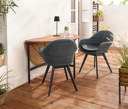 Zwei Schalenstühle mit Polyrattangeflecht stehen an einem Ausklapptisch »Elin«. Auf dem Tisch steht eine LED-Akku-Outdoor-Tischleuchte, schwarz. Im Vordergrund steht ein Pflanzkasten »Elin«.
