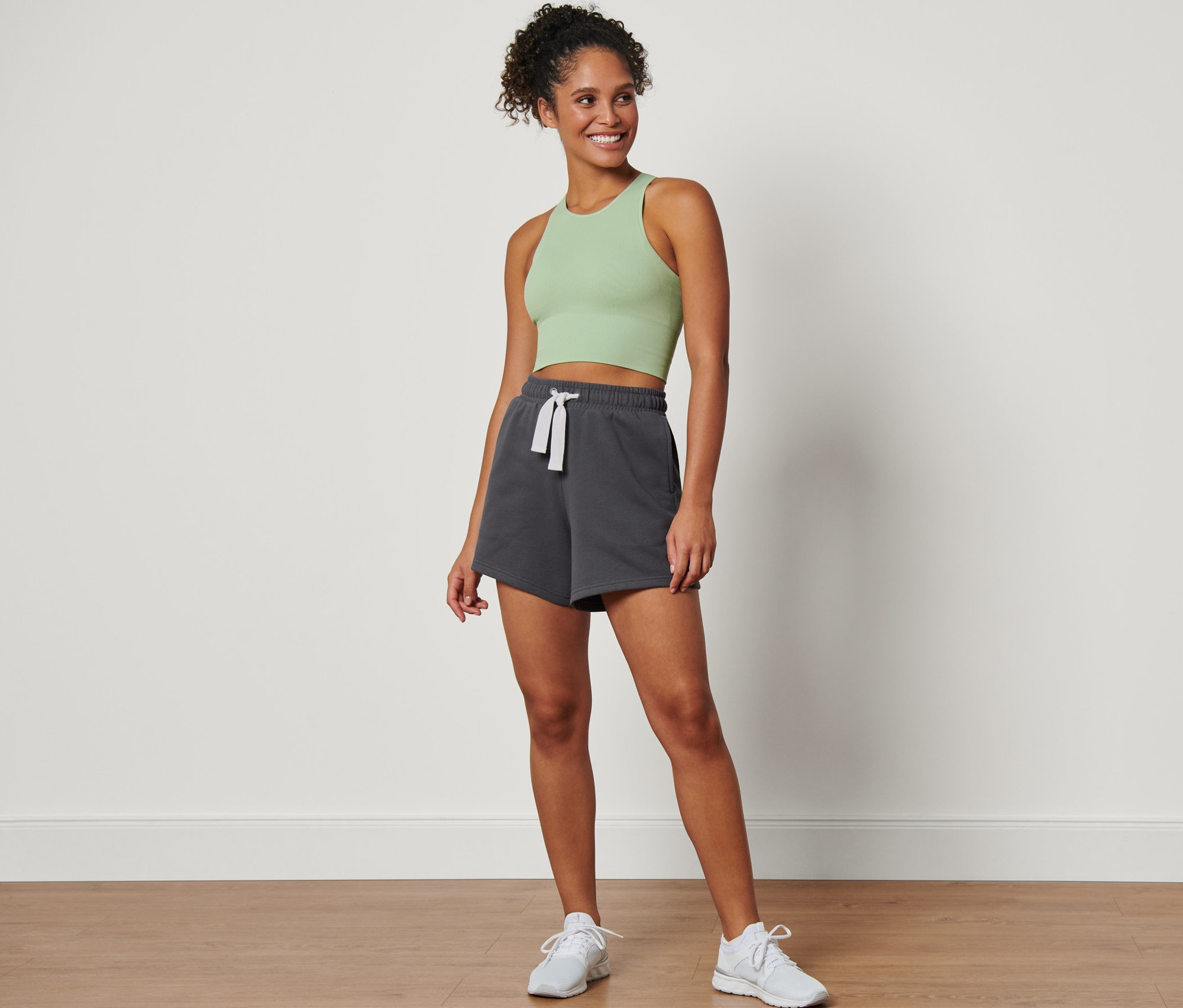 Frau steht und trägt graue Sport-Sweatshorts.