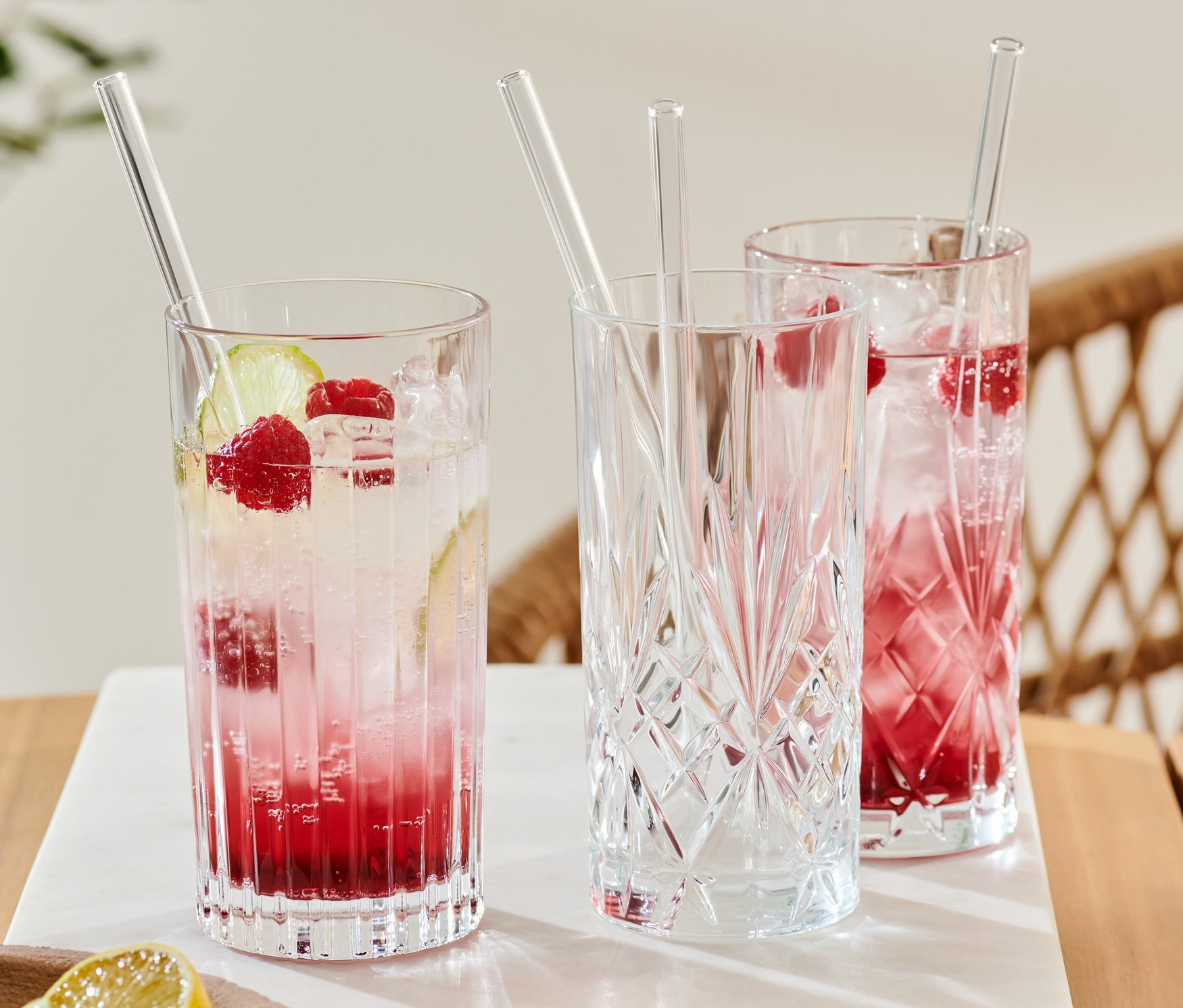Drei Gläser mit Getränken und 4 Glas-Trinkhalme.