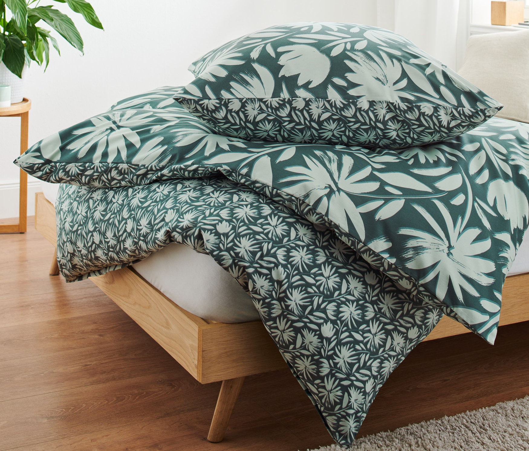 Auf einem Bett liegen drei Garnituren Microfaser-Bettwäsche mit Blumenmuster.