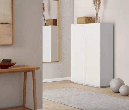 Ein Wandspiegel und ein Highboard in einem Innenraum. Ein Konsolentisch mit 2 Ablagen ist links zu sehen.