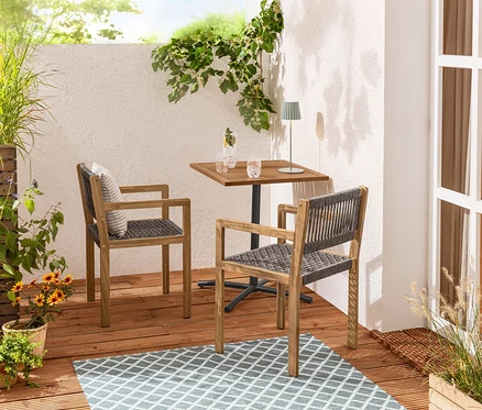 Zwei Dining-Stühle mit Textilgeflecht stehen an einem Balkontisch »Elin« auf einem Outdoor-Wende-Teppich.