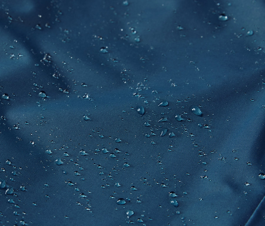 Detailaufnahme einer Kinder-Thermo-Regenhose mit Wassertropfen auf der Oberfläche.