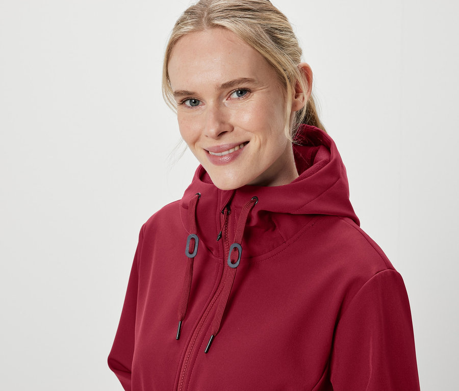 Porträt einer lächelnden Frau in einem burgunderroten Kapuzenpullover.