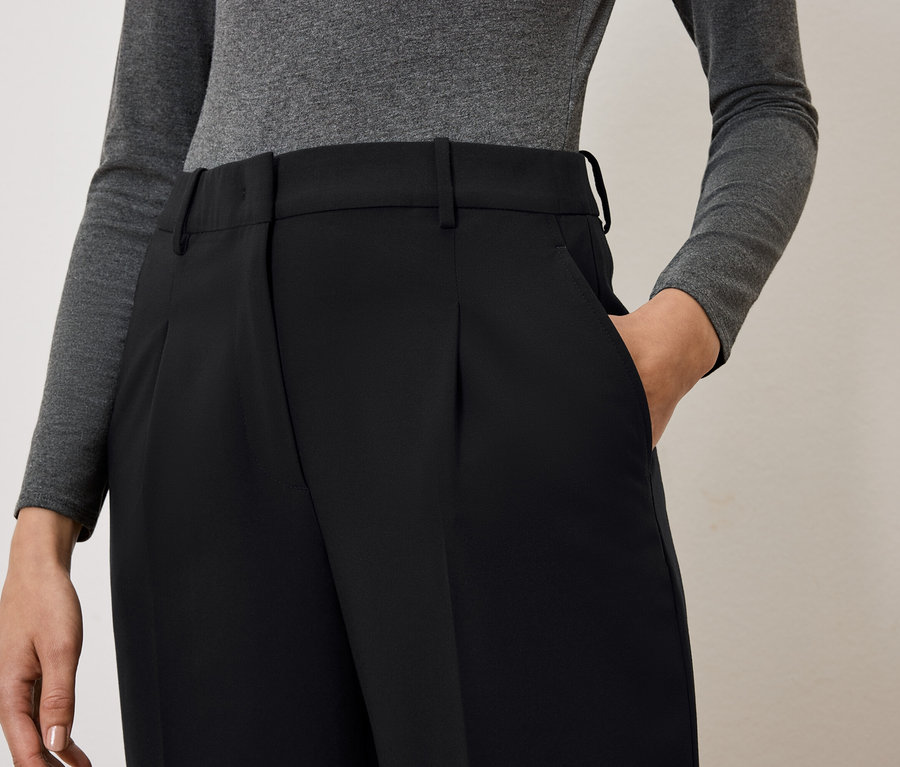 Frau hat Hand in Tasche einer schwarzen Hose.