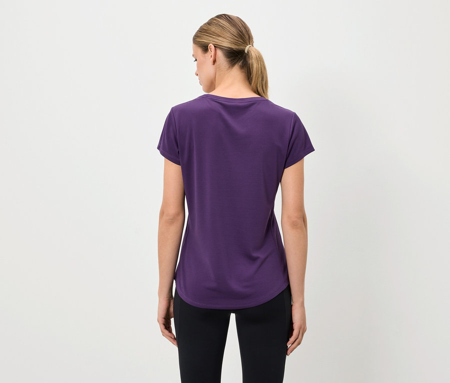 Von hinten ist eine Frau in einem lila T-Shirt und schwarzen Leggings zu sehen.