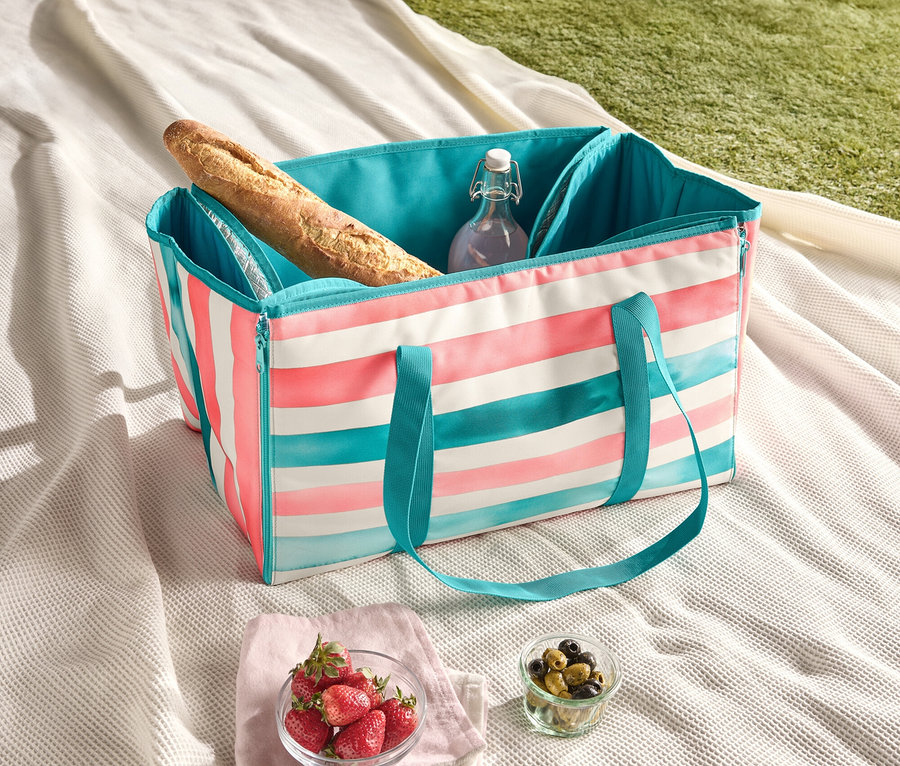 Picknickdecke mit gestreifter Kühltasche, Baguette, Wasserflasche, Erdbeeren und Oliven.