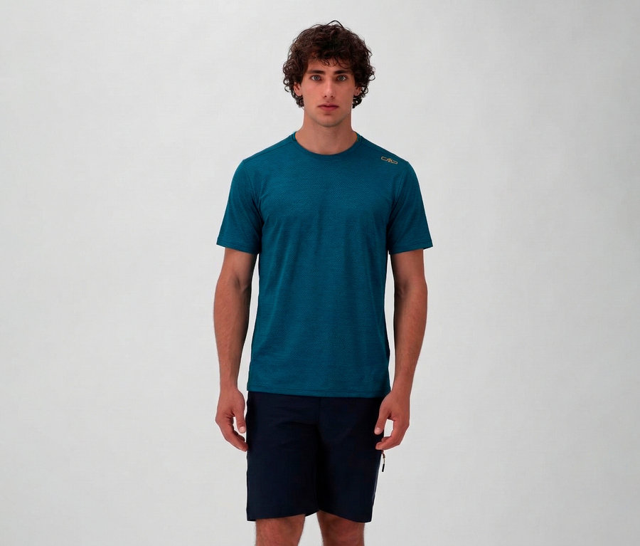 Mann in marineblauen Shorts und einem petrolfarbenen CMP Herren-T-Shirt aus Piquéstrick vor einem neutralen Hintergrund.