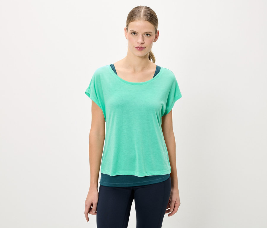 Frau trägt ein grünes T-Shirt und blaue Leggings.