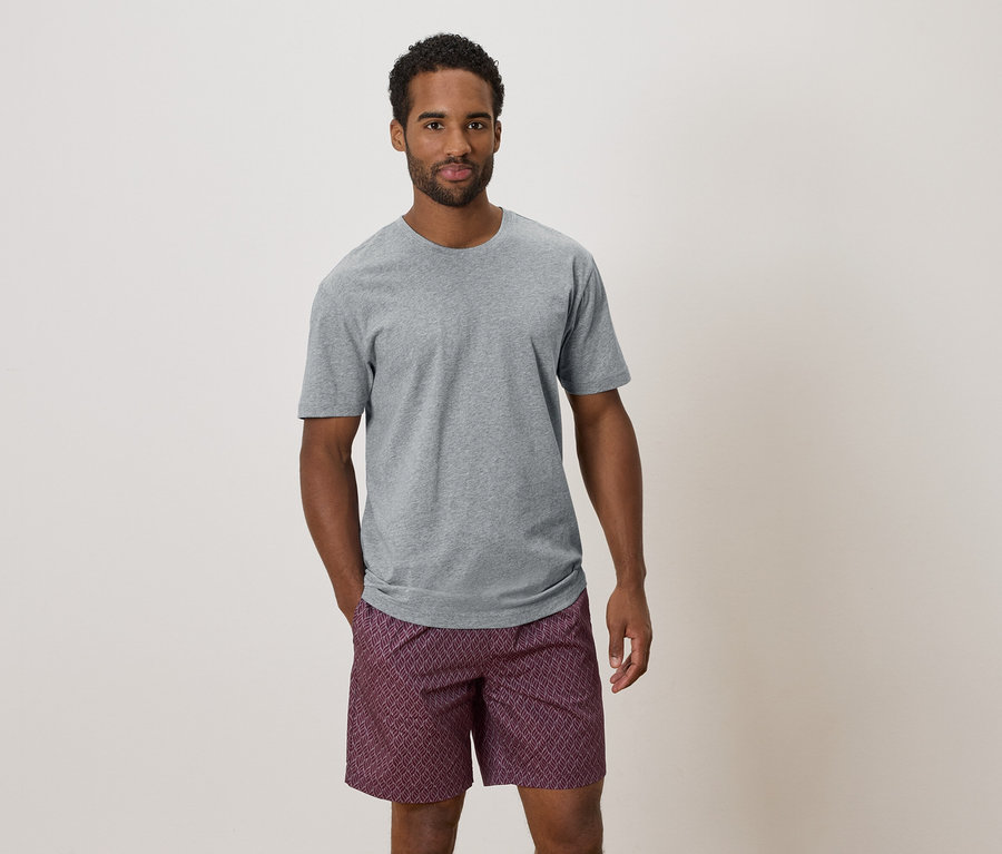 Mann mit grauem T-Shirt und gemusterter Shorts