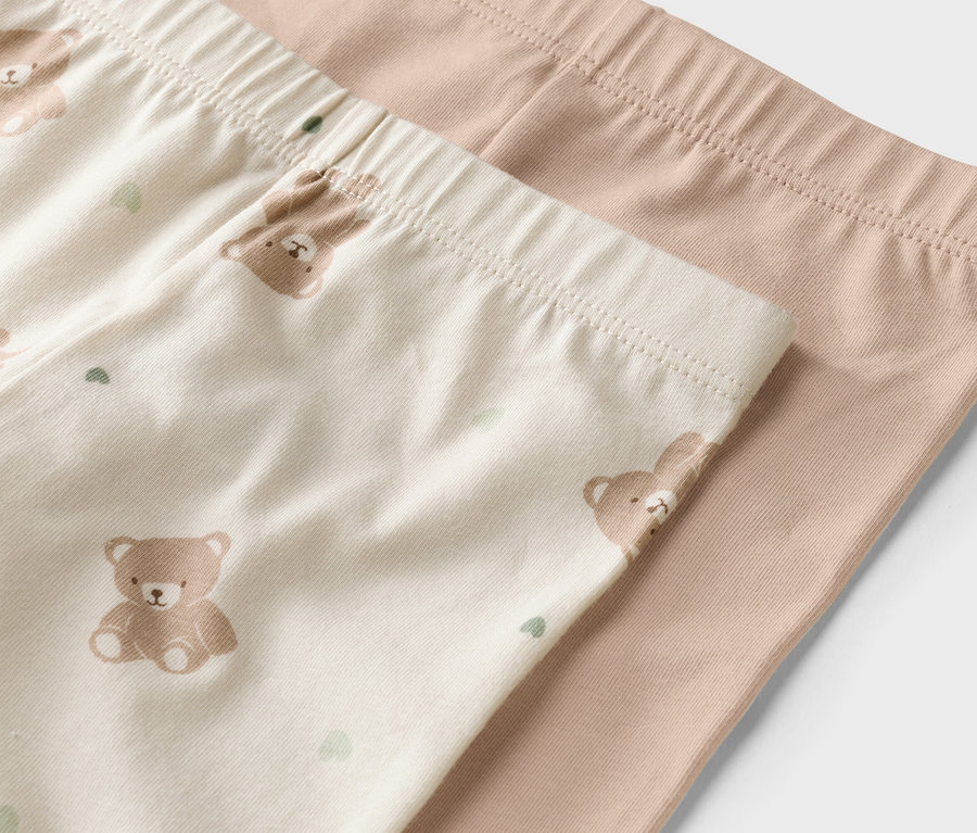 Nahaufnahme von zwei Leggings, eine beige mit Bärenmuster, die andere einfarbig hellbraun.