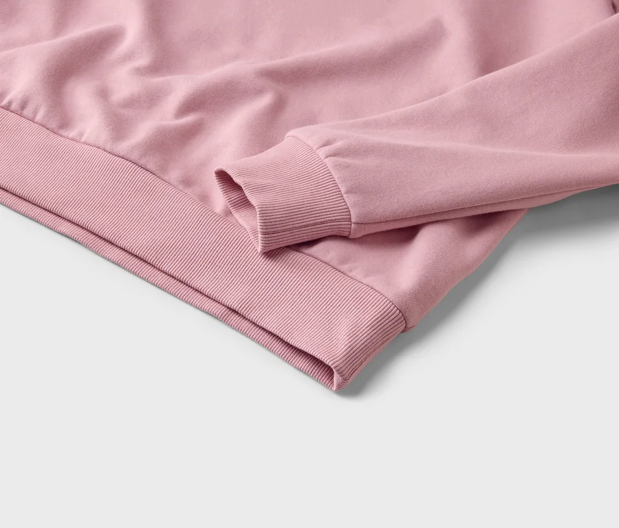 Nahaufnahme eines rosa Sweatshirts, das den gerippten Ärmelbund und den gerippten Saum zeigt.