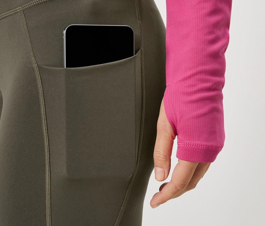 Frau trägt Leggings mit Handytasche und pinkfarbenes Oberteil.