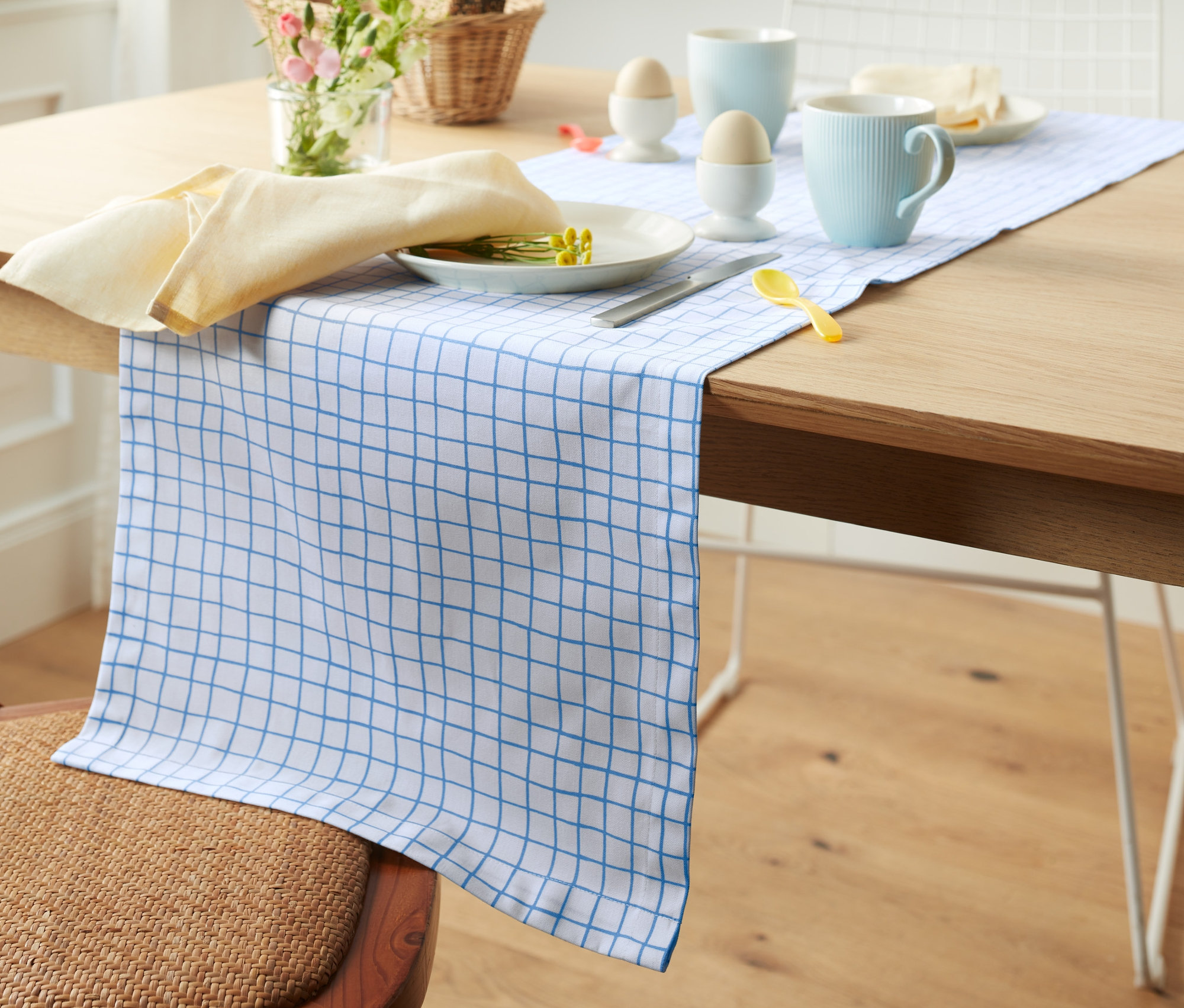 Tisch mit Tischläufer mit Alloverprint, Teller, Tasse und Serviette sind aufgedeckt.