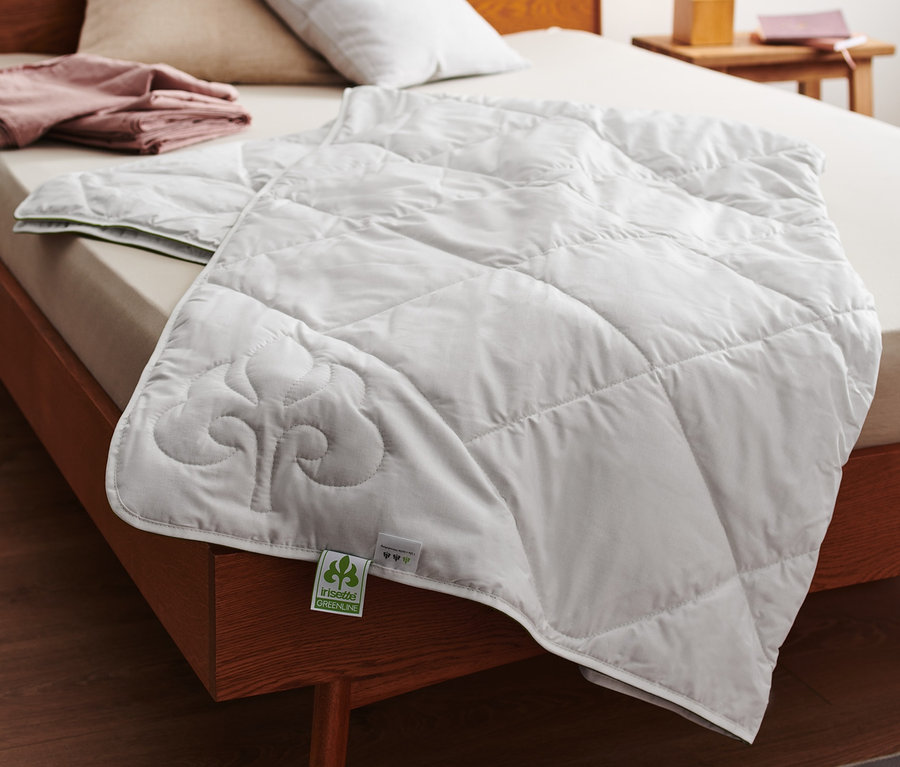 Auf einem Bett liegt ein weißes irisette® greenline Baumwoll-Leinen-Sommer-Steppbett.