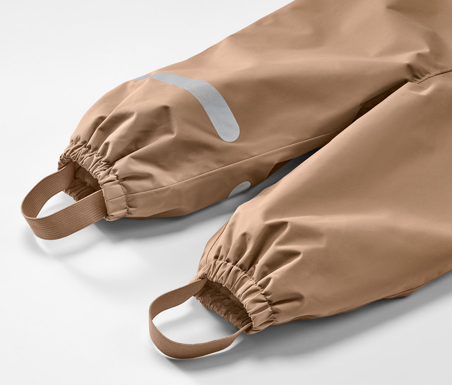 Detail einer Kinder-Thermo-Regenhose, braun, mit elastischen Bündchen und Reflektoren.