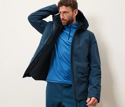 Mann posiert in Outdoorjacke mit Weste.
