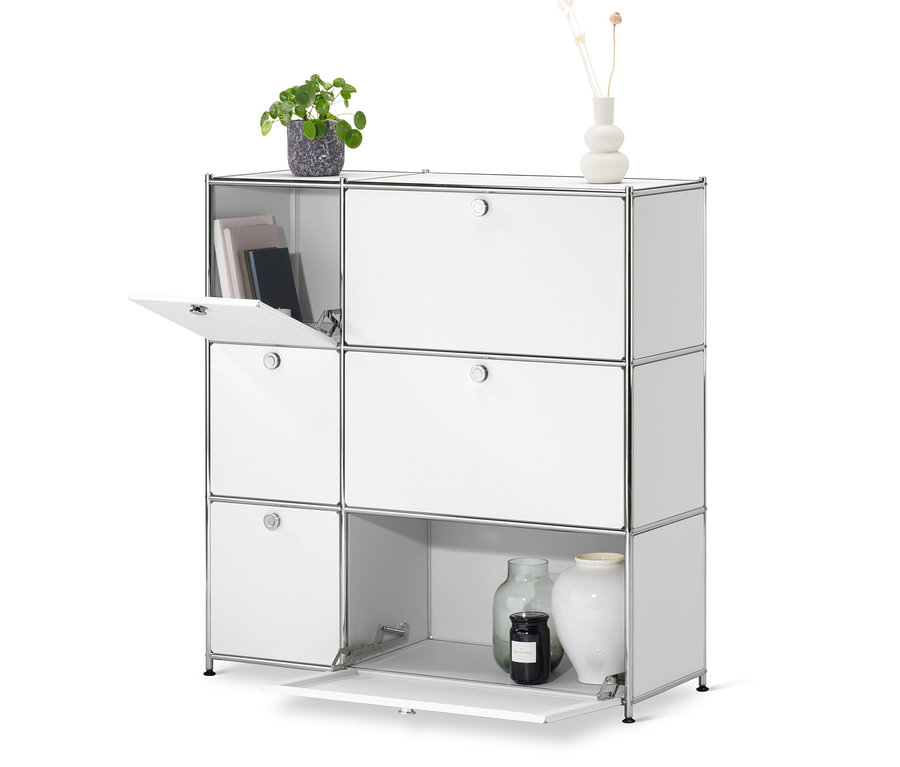 Eine weiße Kommode »CN3« mit 6 Klappen, von denen eine geöffnet ist. Auf der Kommode stehen eine Vase mit Blumen und ein Blumentopf.