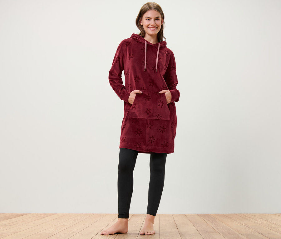 Frau steht mit Händen in den Taschen eines Nicki-Loungewear-Kleids mit Sternen.