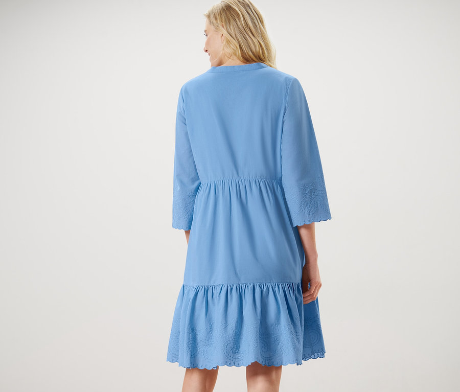 Frau trägt ein Webkleid mit Stickerei.