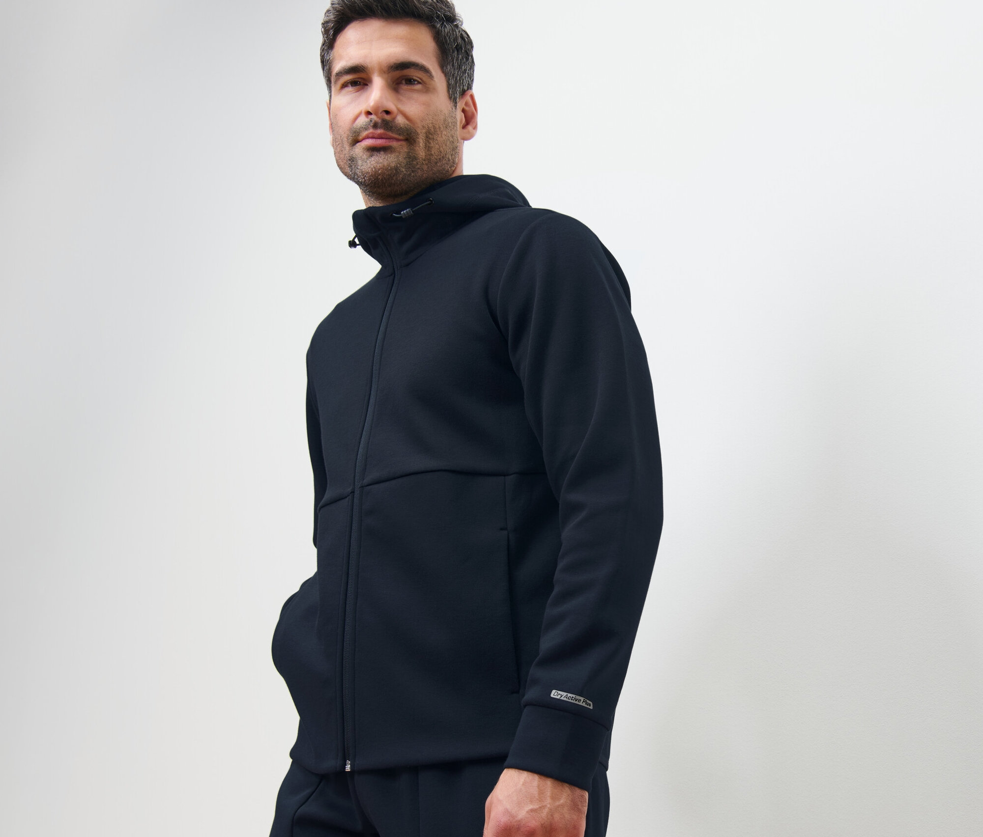 Mann posiert in dunkelblauer Funktionssweatjacke.