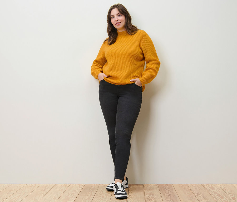 Frau posiert in Grobstrickpullover und Slim Jeans – Fit »Emma«.