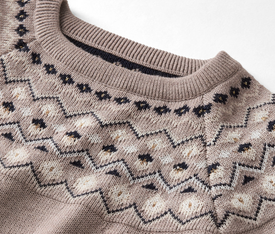 Detailaufnahme eines beigen Pullovers mit Muster.