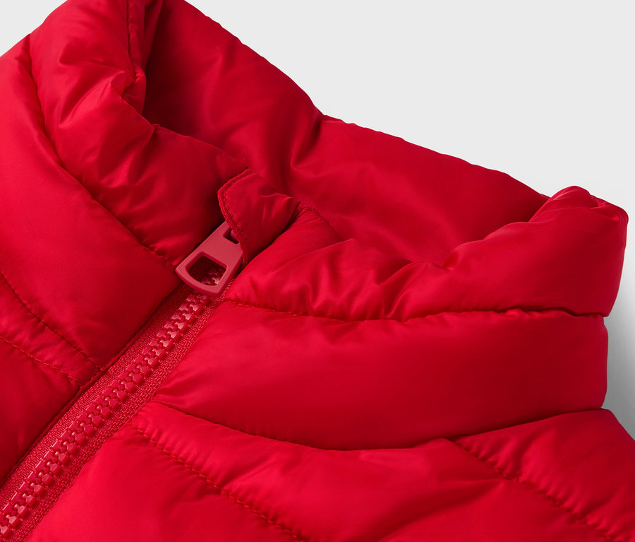 Detail einer roten Steppweste mit rotem Reißverschluss.
