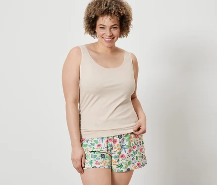 Frau trägt ein cremefarbenes Hemdchen und blumige Shorts von 2 Shorts und 2 Hemdchen.