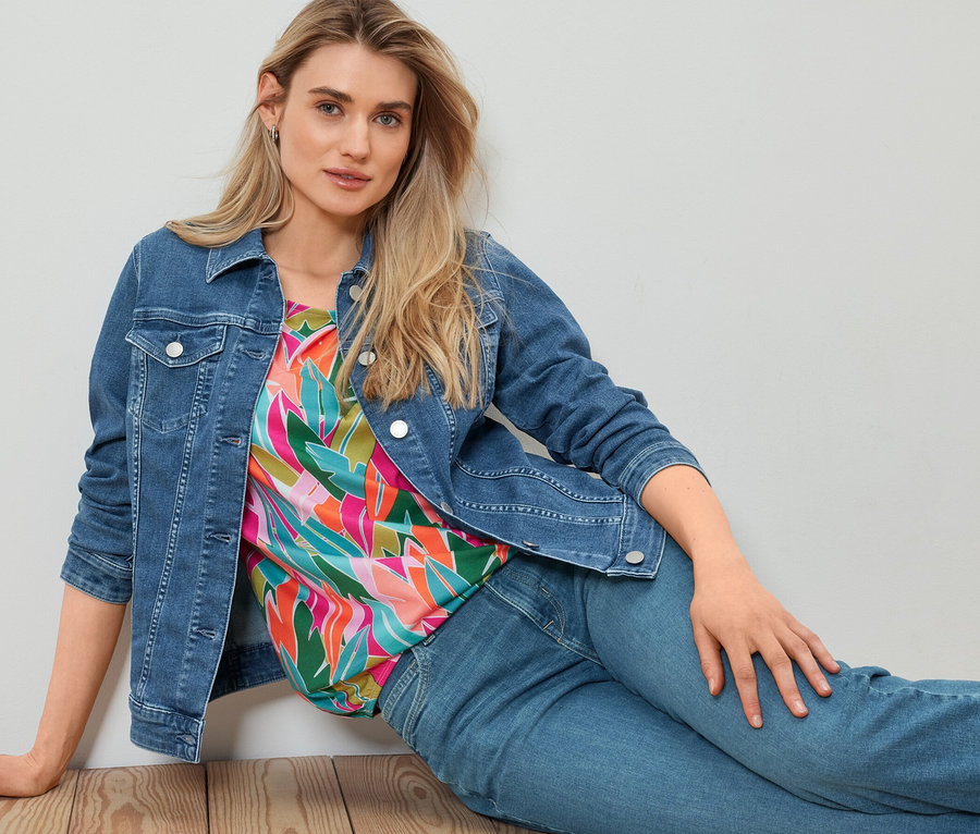 Frau sitzt auf dem Boden und trägt eine Jeansjacke.