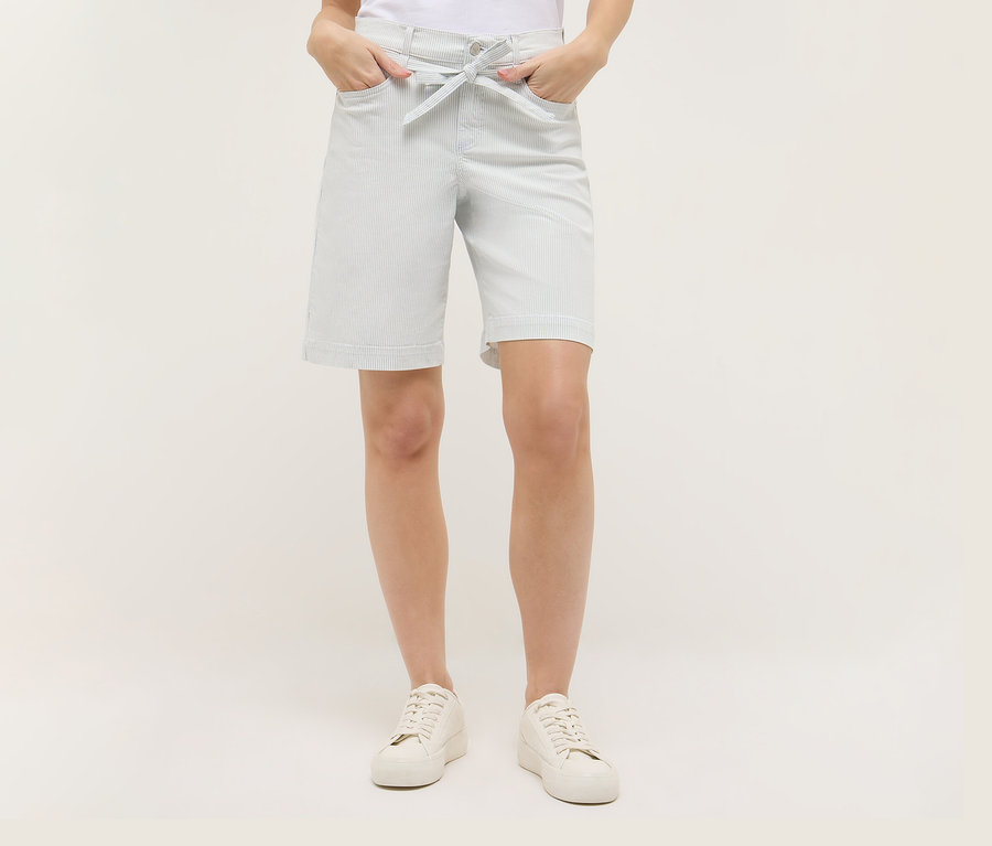 Frau mit Angels Denim »Lia City« Shorts mit Streifen und weißen Schuhen. Sie hat ihre Hände in den Hosentaschen.