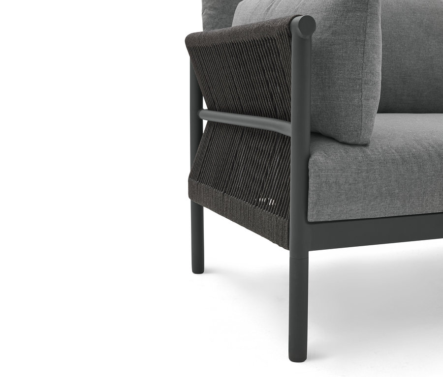Nahaufnahme eines grauen Sessels mit dunkler Kordelbespannung an der Seite.