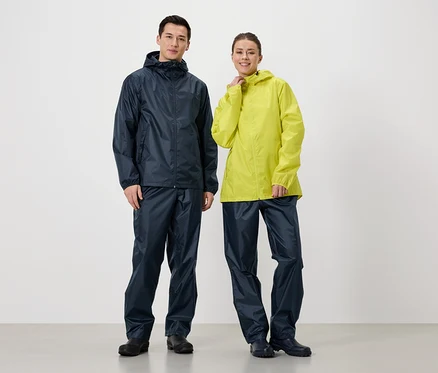 Ein Mann in marineblauer Regenjacke und Regenhose steht neben einer Frau in gelber Regenjacke und marineblauer Regenhose.