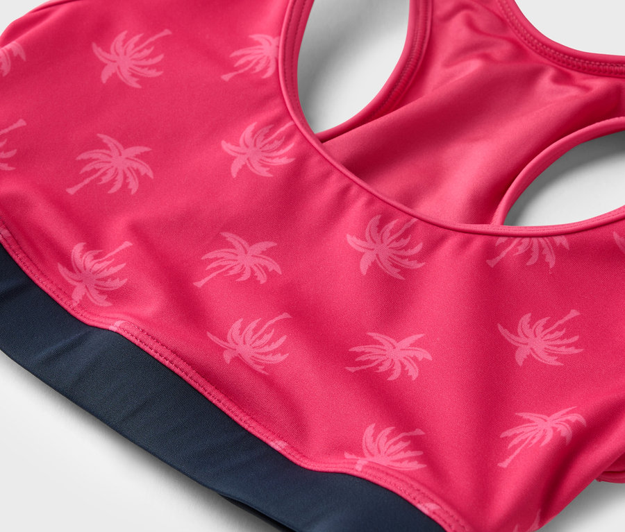 Nahaufnahme eines pinkfarbenen Sport-BHs mit Palmenmuster und marineblauem Bund.