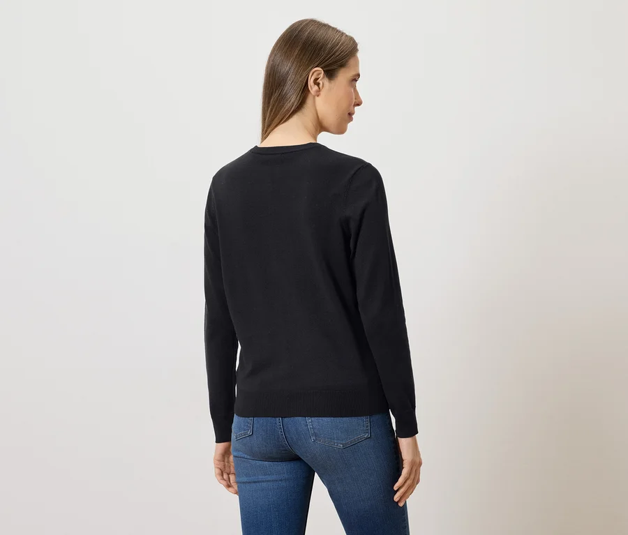Rückansicht einer Frau mit langen braunen Haaren, die einen schwarzen Pullover und blaue Jeans trägt.
