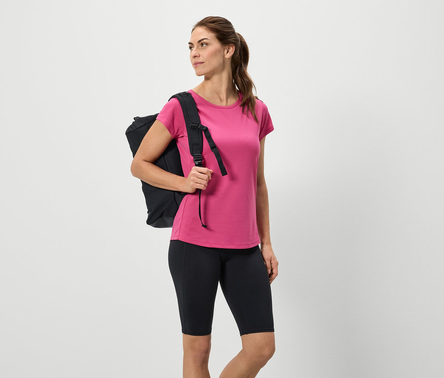 Frau mit schwarzem Rucksack, pinkem T-Shirt und schwarzen Shorts.