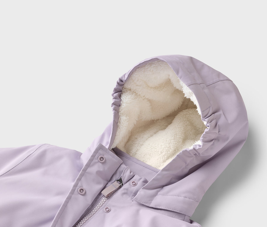 Nahaufnahme einer lila Jacke mit Kapuze und cremefarbenem Fleecefutter. Der Reißverschluss und Druckknöpfe sind sichtbar.
