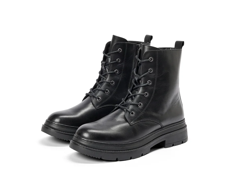 Zwei schwarze Combat-Boots mit Schnürsenkeln und seitlichen Reißverschlüssen, mit dicken, geriffelten Sohlen, auf weißem Hintergrund.
