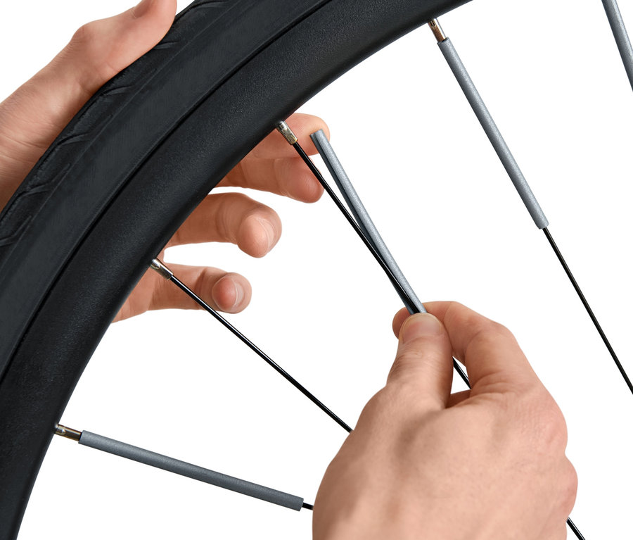 Hände montieren 36 Speichen-Reflektoren an einem Fahrrad.