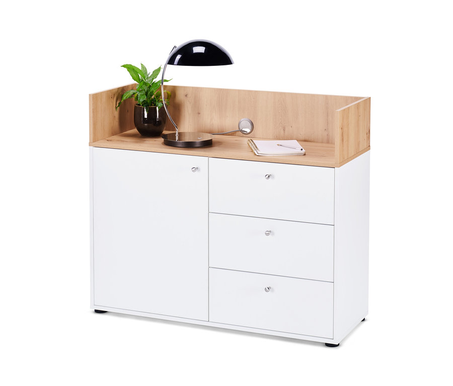 Ein Sideboard mit Schubladen und Tür, darauf eine Topfpflanze, eine Lampe und ein Notizbuch.