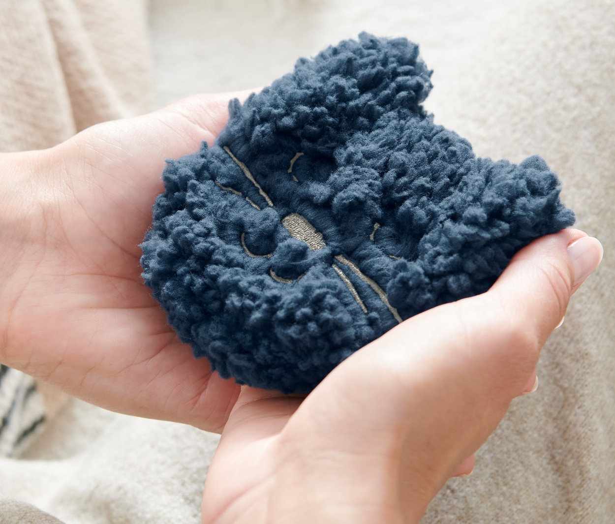 Eine Person hält zwei Taschenheizkissen, »Katze« in den Händen.