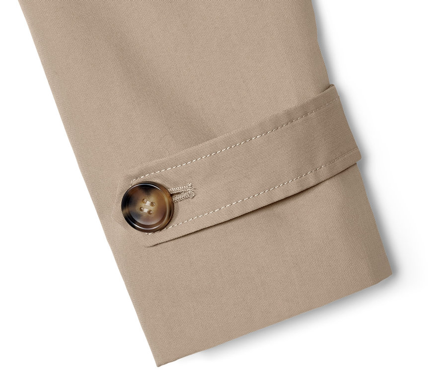 Detailansicht eines beigen Trenchcoats mit braunem Knopf.