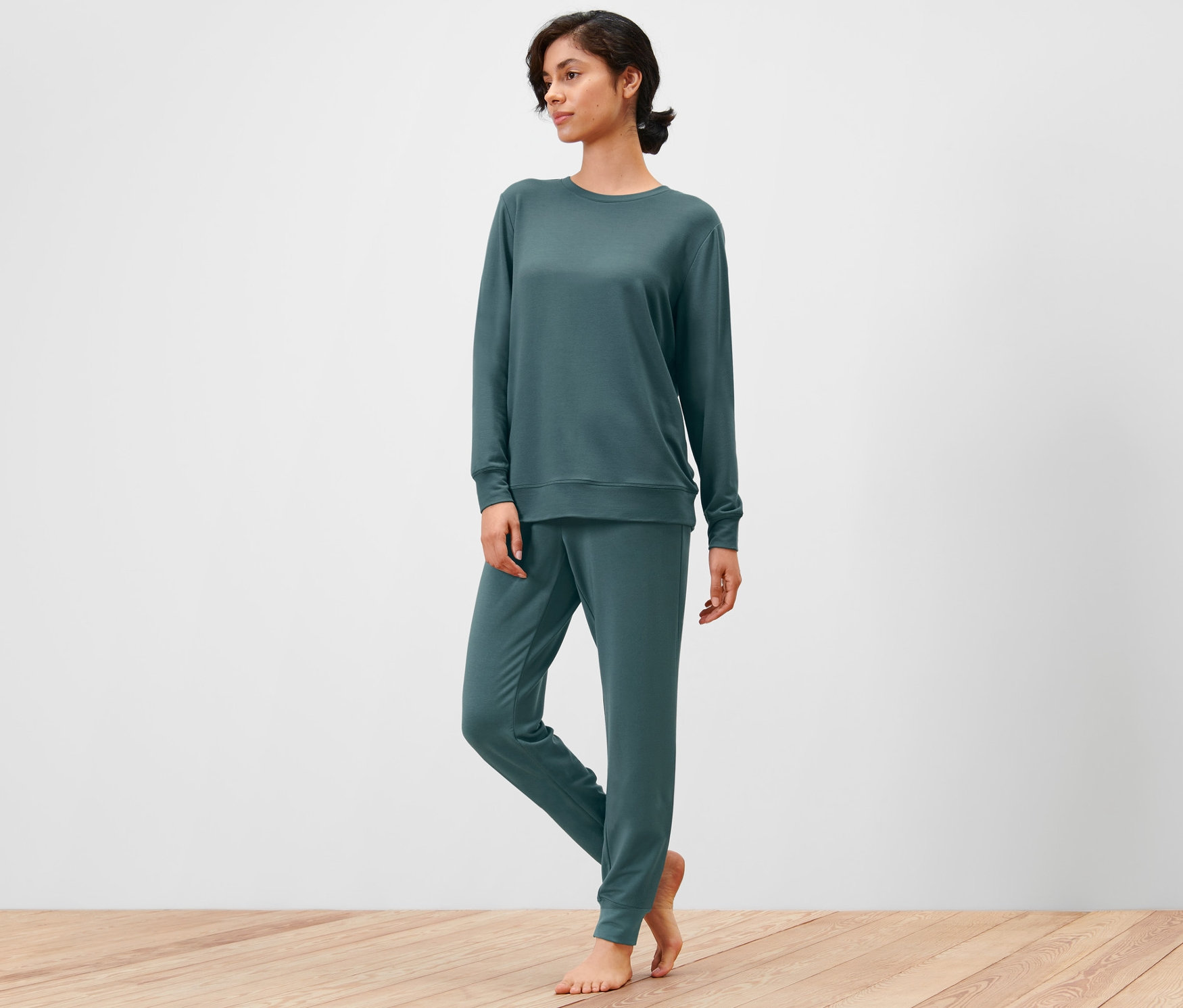 Frau im Hausanzug steht auf Holzboden.