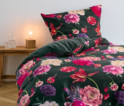 Grüne Biber-Bettwäsche mit Blumenmuster auf einem Bett.