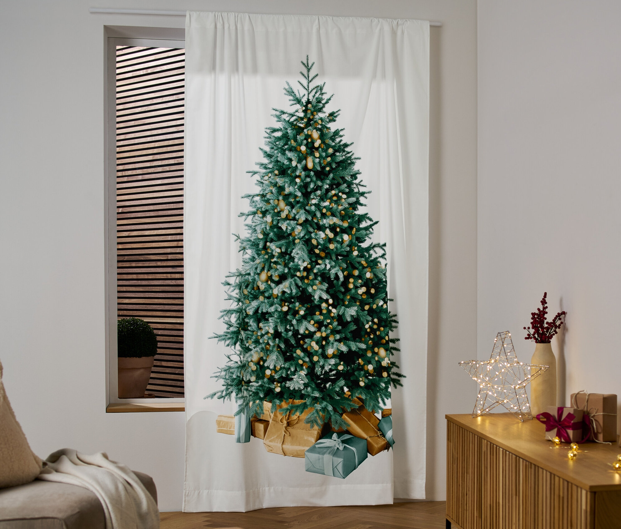 Weißer Motiv-Vorhang mit Weihnachtsbaum hängt am Fenster.